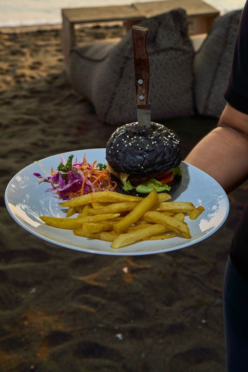 Black-bun burger and fries served on the beach